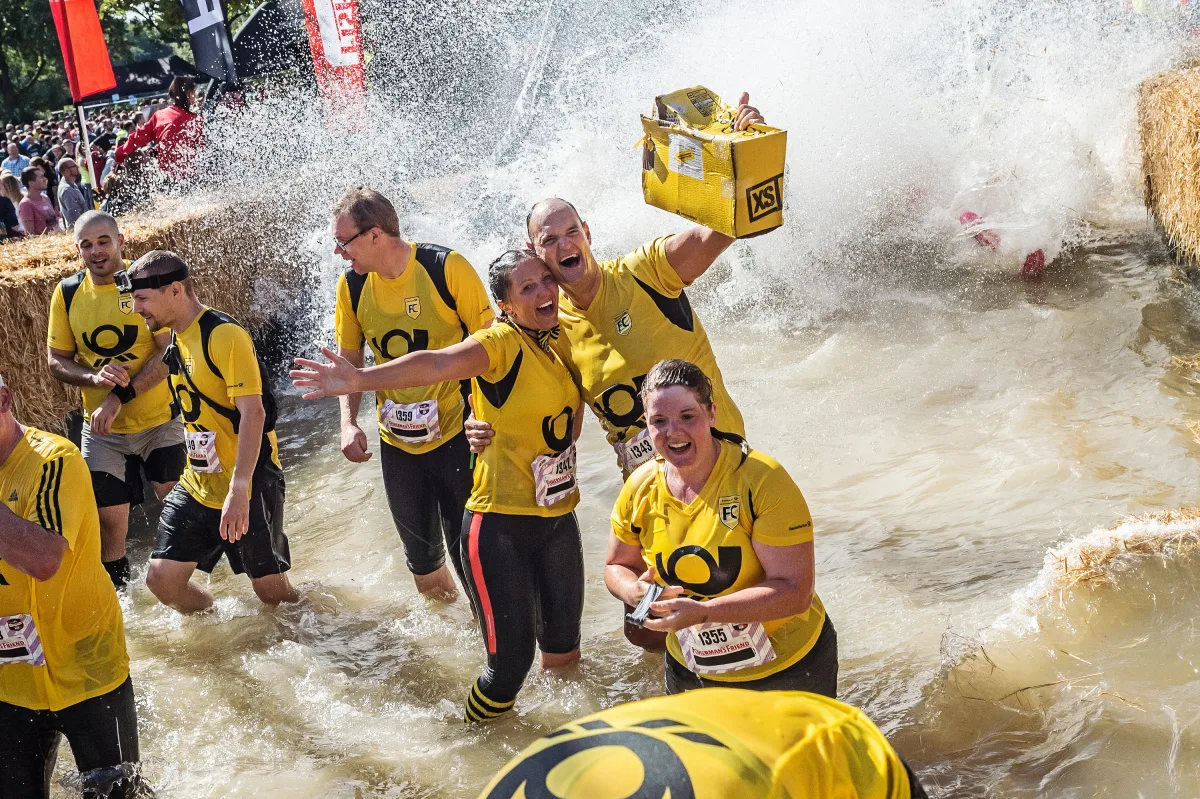 Firmenteam gemeinsam im Wasserhindernis beim Hotfoot Run